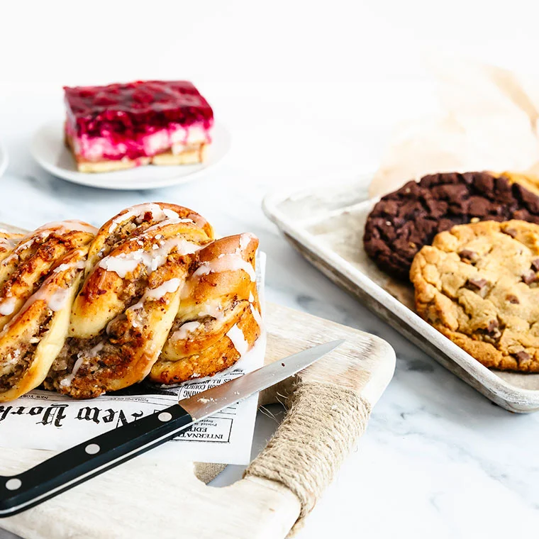Verschiedene Backwaren wie Zimtschnecken, Kekse und ein Himbeer-Kuchenstück.