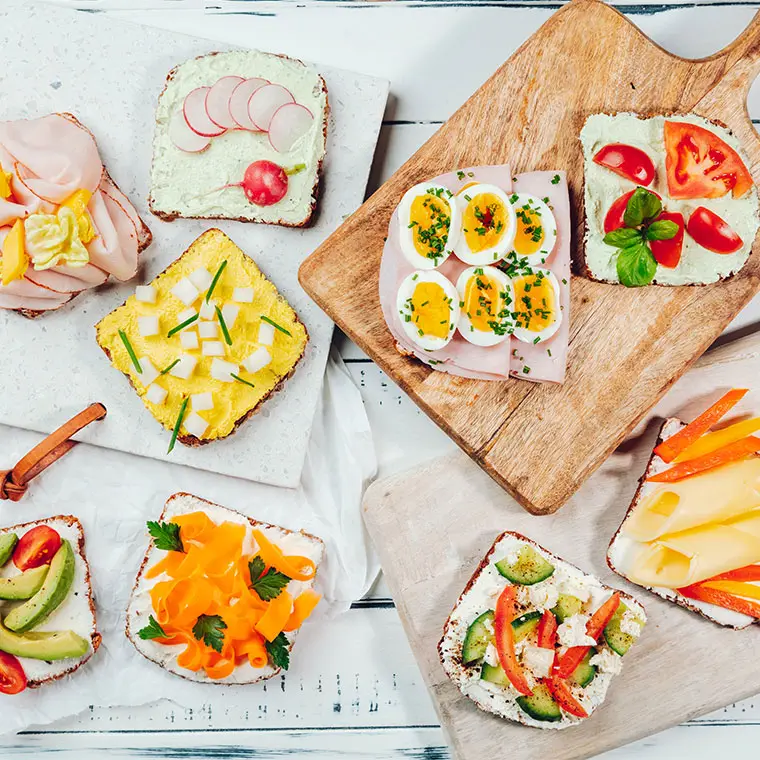 Eine Auswahl an belegten Broten mit frischen Zutaten wie Eiern, Gemüse, Käse und Aufschnitt.